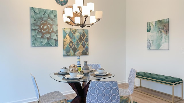 dining space featuring a notable chandelier, baseboards, and wood finished floors