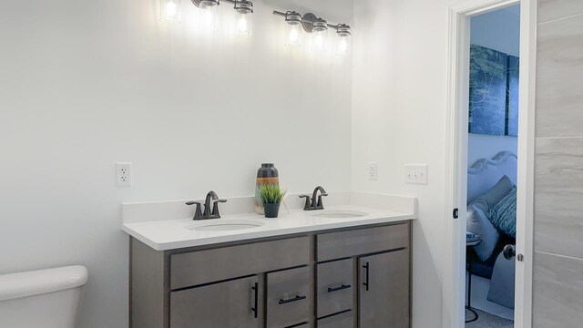 bathroom with toilet and dual bowl vanity