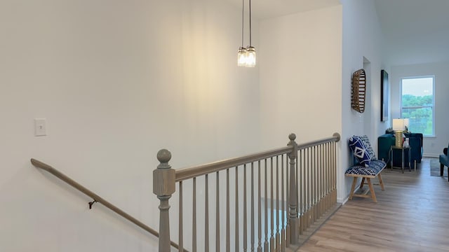 corridor with light wood-style flooring, baseboards, and an upstairs landing