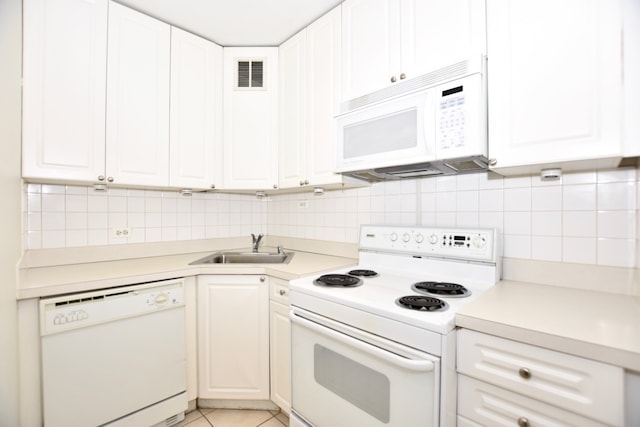 kitchen with white appliances, backsplash, light tile floors, sink, and white cabinetry