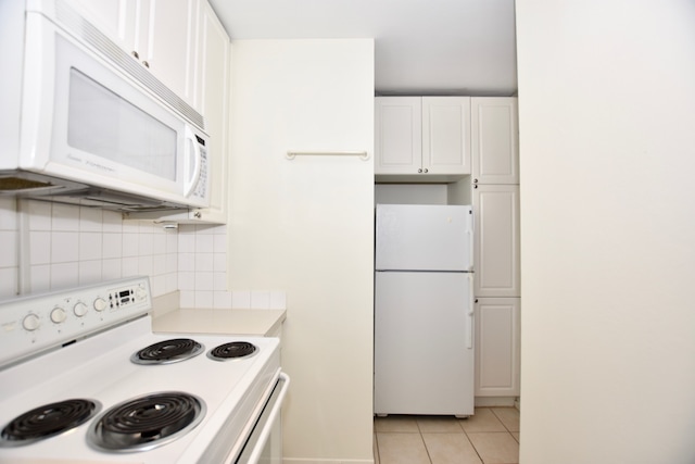 kitchen with light tile floors, white appliances, white cabinetry, and backsplash