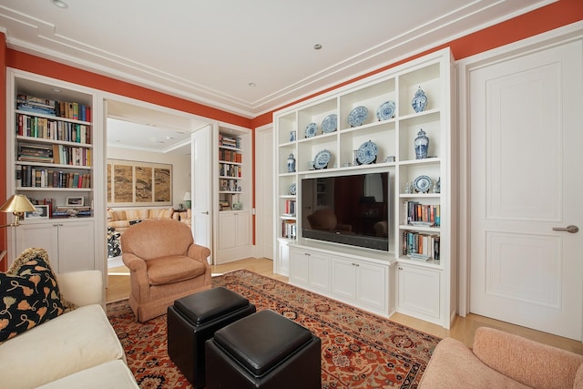 living room with built in features, wood-type flooring, and ornamental molding