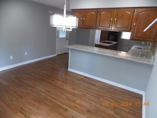 kitchen featuring dark hardwood / wood-style flooring, light stone countertops, kitchen peninsula, and a chandelier