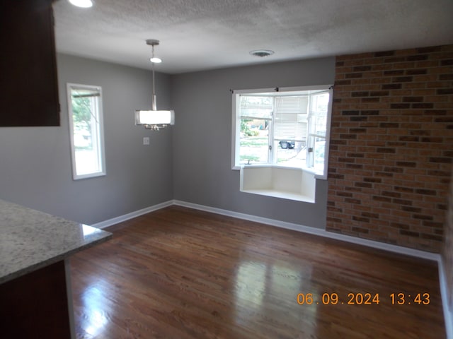 unfurnished dining area with a textured ceiling and dark wood-type flooring