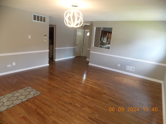 spare room featuring dark hardwood / wood-style flooring and a notable chandelier