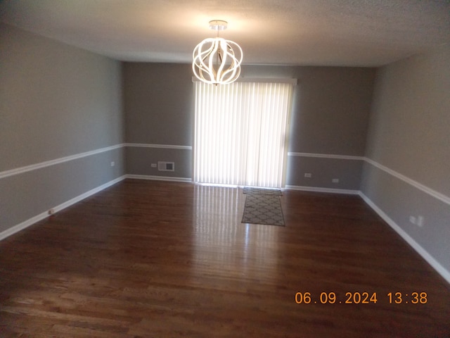 spare room with dark hardwood / wood-style flooring and a notable chandelier