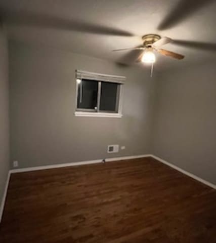 spare room with dark hardwood / wood-style flooring and ceiling fan