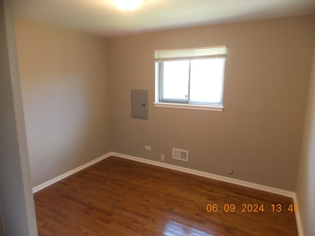 empty room with dark hardwood / wood-style floors and electric panel