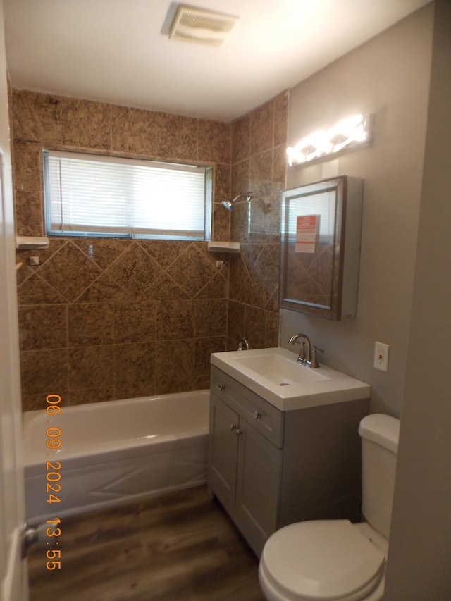 full bathroom featuring toilet, vanity, hardwood / wood-style flooring, and tiled shower / bath combo