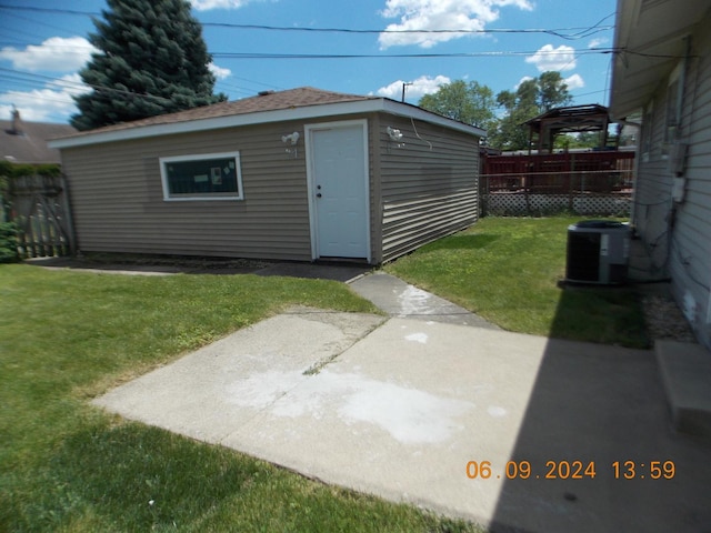 view of outdoor structure with a lawn and central air condition unit