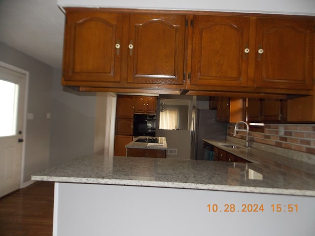 kitchen featuring light stone countertops, dark hardwood / wood-style floors, black appliances, and sink