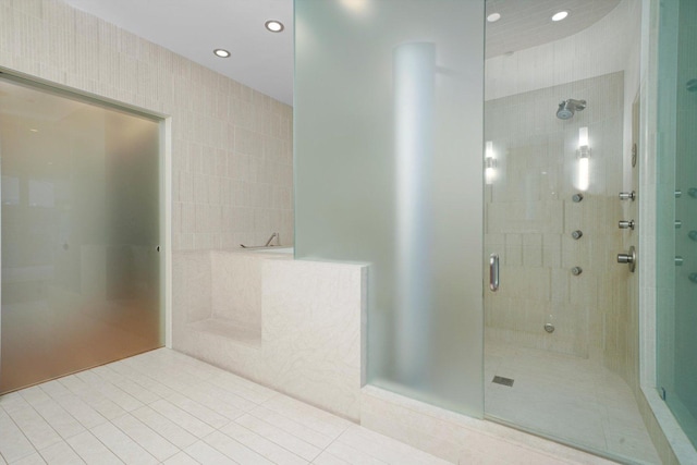 bathroom with tile patterned floors, a shower with door, and tile walls