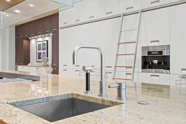 kitchen featuring dark brown cabinetry, white cabinetry, sink, and oven