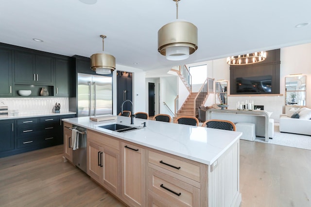 15W601 Grant St, Burr Ridge, IL 60527 - kitchen featuring a center island with sink, sink, appliances with stainless steel finishes, light brown cabinetry, and decorative light fixtures