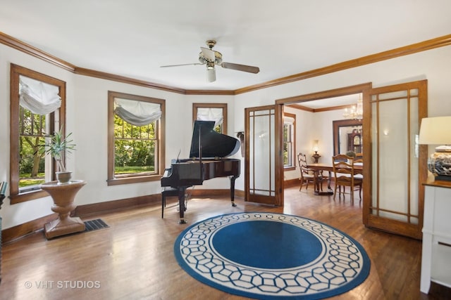 living area with ceiling fan with notable chandelier, wood finished floors, baseboards, and ornamental molding