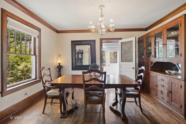 dining area with dark wood finished floors, plenty of natural light, crown molding, and an inviting chandelier