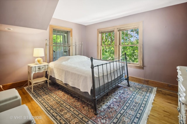 bedroom featuring baseboards, multiple windows, and wood finished floors