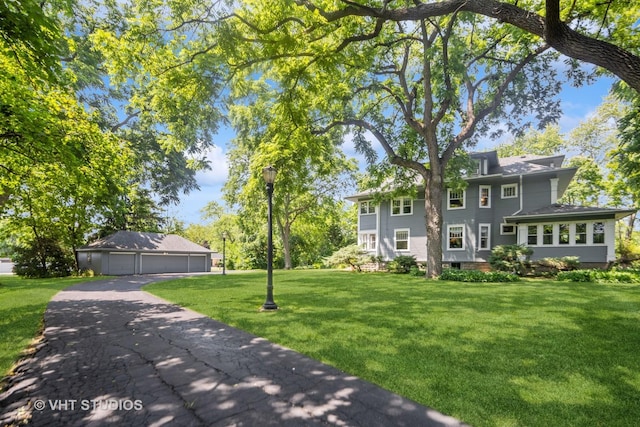 view of front of home with a garage, an outbuilding, and a front lawn