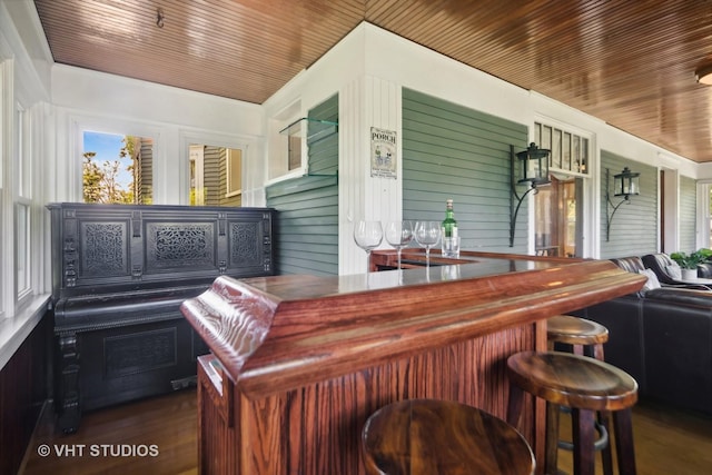 bar with a bar, wood ceiling, and dark wood finished floors