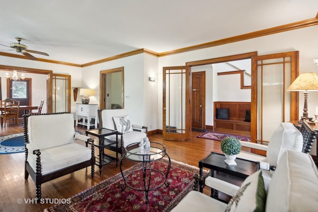 living area with ceiling fan, wood finished floors, baseboards, and ornamental molding