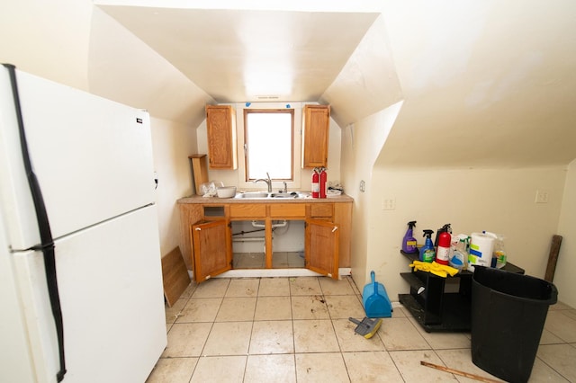 kitchen with white refrigerator, lofted ceiling, and sink