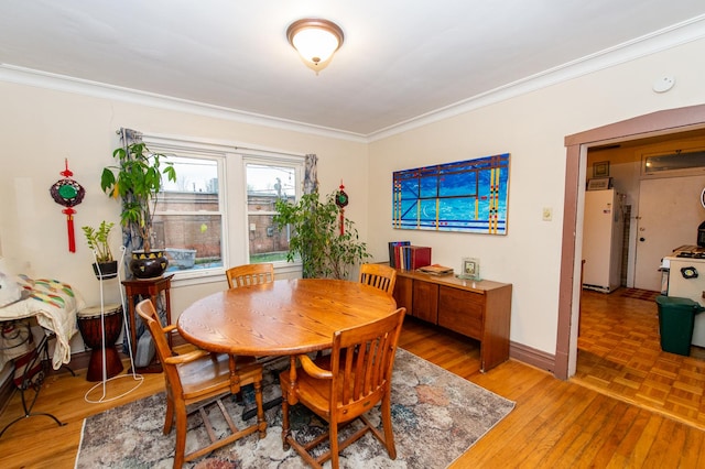 dining space featuring wood-type flooring and ornamental molding