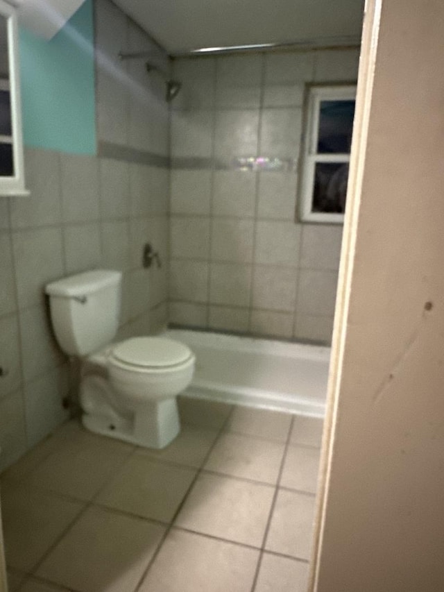 bathroom with tile patterned flooring, a tile shower, and toilet