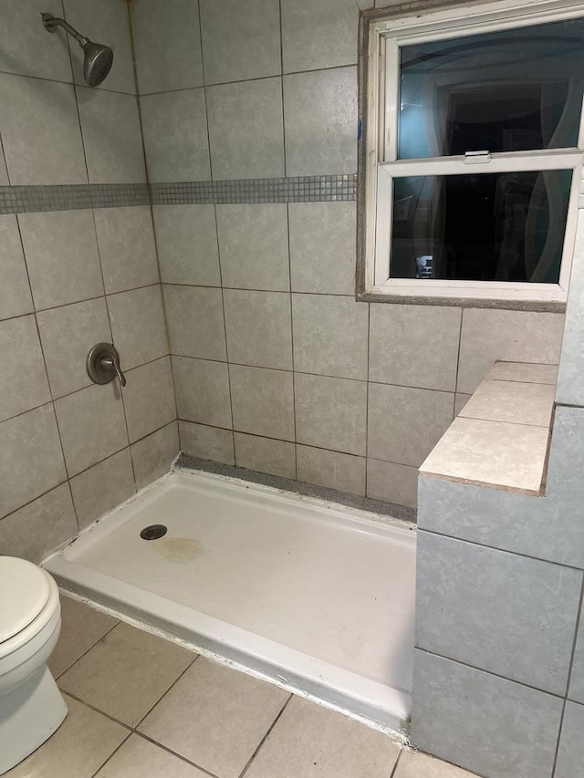 bathroom with a tile shower, tile patterned flooring, and toilet