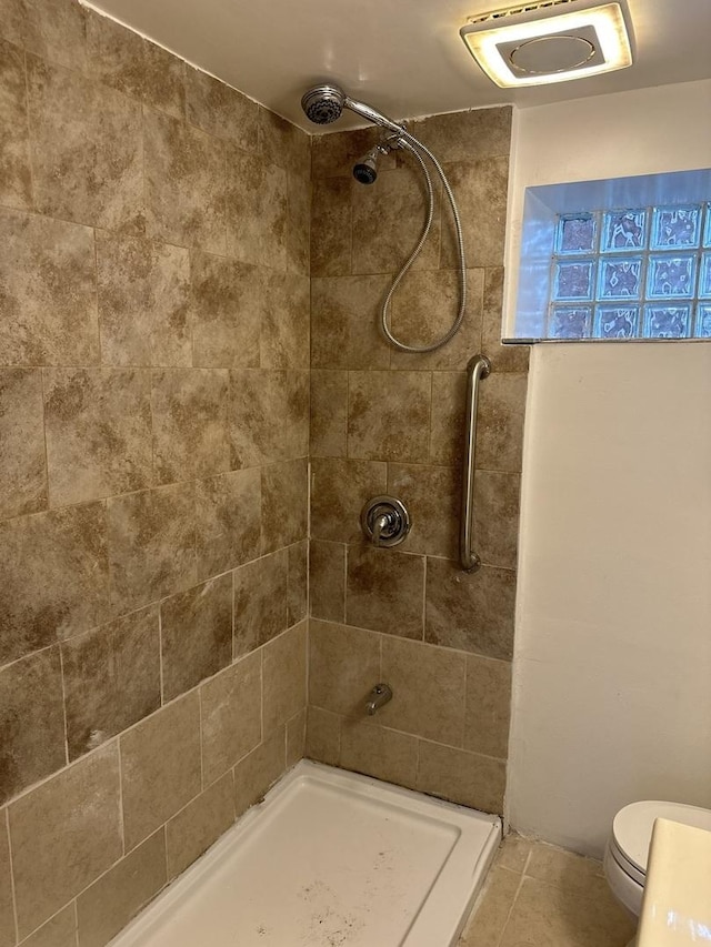 bathroom with tiled shower, tile patterned floors, and toilet