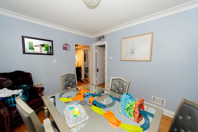 dining space with wood-type flooring and ornamental molding