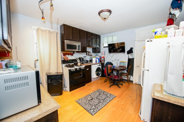 kitchen featuring black gas stove, light wood-type flooring, white fridge, washer / dryer, and dark brown cabinetry