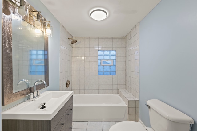 full bathroom featuring tile flooring, tiled shower / bath combo, toilet, and vanity with extensive cabinet space