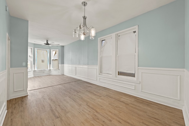 unfurnished room featuring ceiling fan with notable chandelier and wood-type flooring