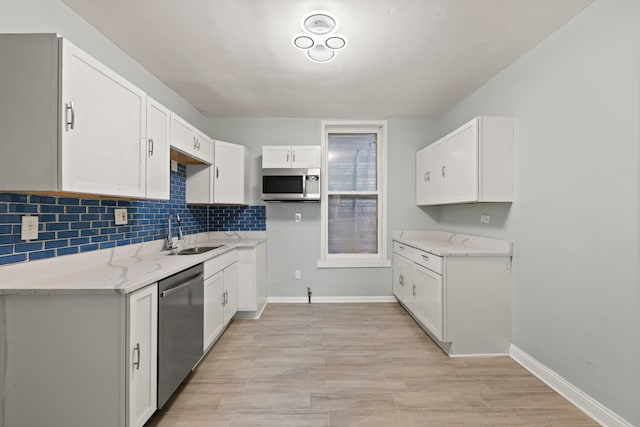 kitchen featuring sink, white cabinets, light stone counters, and stainless steel appliances