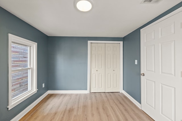 unfurnished bedroom with a closet and light hardwood / wood-style floors