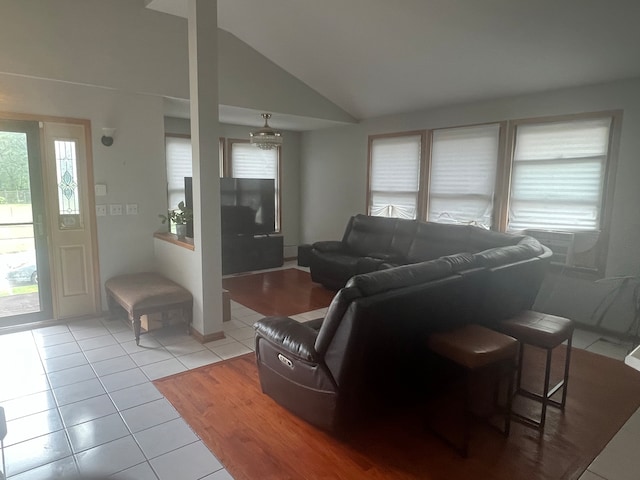 tiled living room with cooling unit and vaulted ceiling