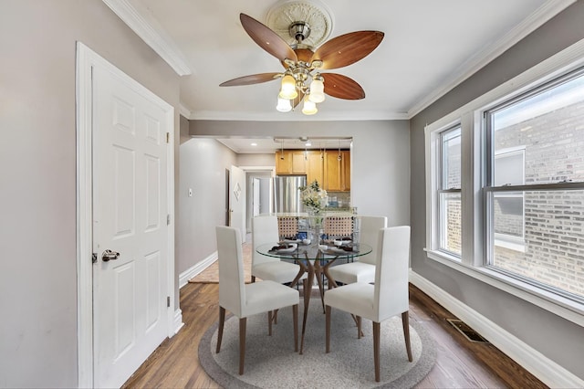 dining room featuring ceiling fan, ornamental molding, and dark wood-type flooring