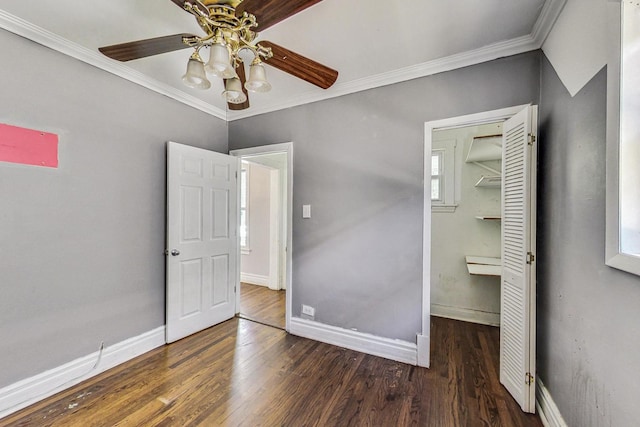 unfurnished bedroom with ceiling fan, crown molding, dark wood-type flooring, multiple windows, and a closet