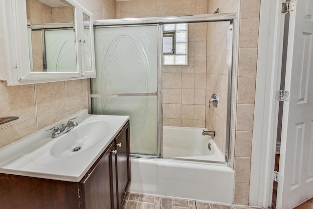 bathroom with decorative backsplash, vanity, tile walls, and bath / shower combo with glass door