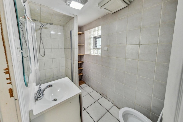 bathroom with tile patterned flooring, vanity, tiled shower, and tile walls