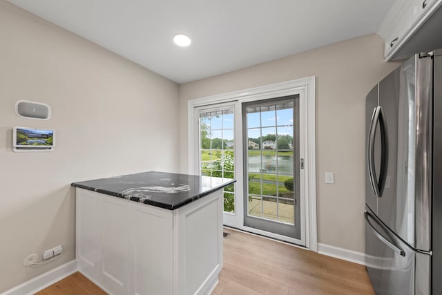 kitchen featuring light wood-type flooring, freestanding refrigerator, white cabinets, and a water view