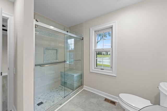 bathroom with toilet, a shower stall, visible vents, and baseboards