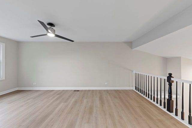 empty room with light wood-type flooring, vaulted ceiling with beams, ceiling fan, and baseboards