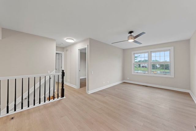 empty room featuring a ceiling fan, light wood-style flooring, and baseboards