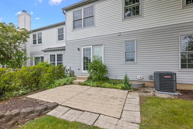 back of house with entry steps, a patio area, a chimney, and cooling unit