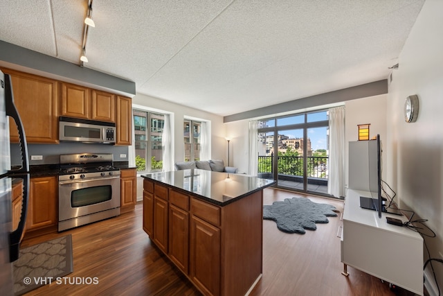 kitchen featuring dark hardwood / wood-style flooring, stainless steel appliances, a center island, track lighting, and a textured ceiling