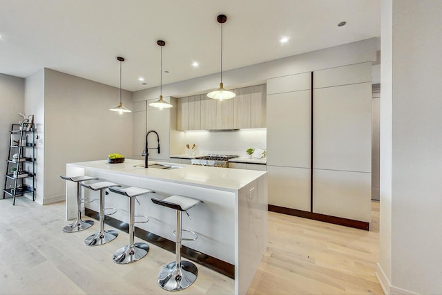 kitchen with sink, pendant lighting, a center island with sink, and light hardwood / wood-style floors