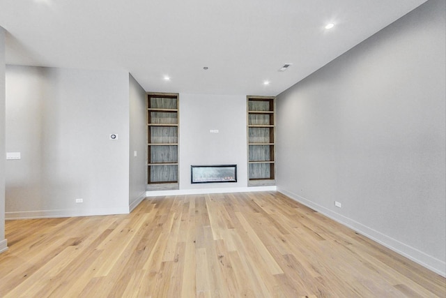 unfurnished living room with built in features and light hardwood / wood-style floors