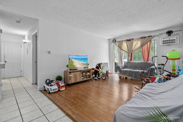 living room featuring light hardwood / wood-style floors, a textured ceiling, and a wall mounted AC