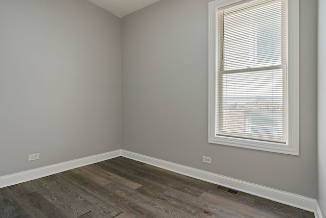 unfurnished room featuring dark wood-style floors, visible vents, and baseboards